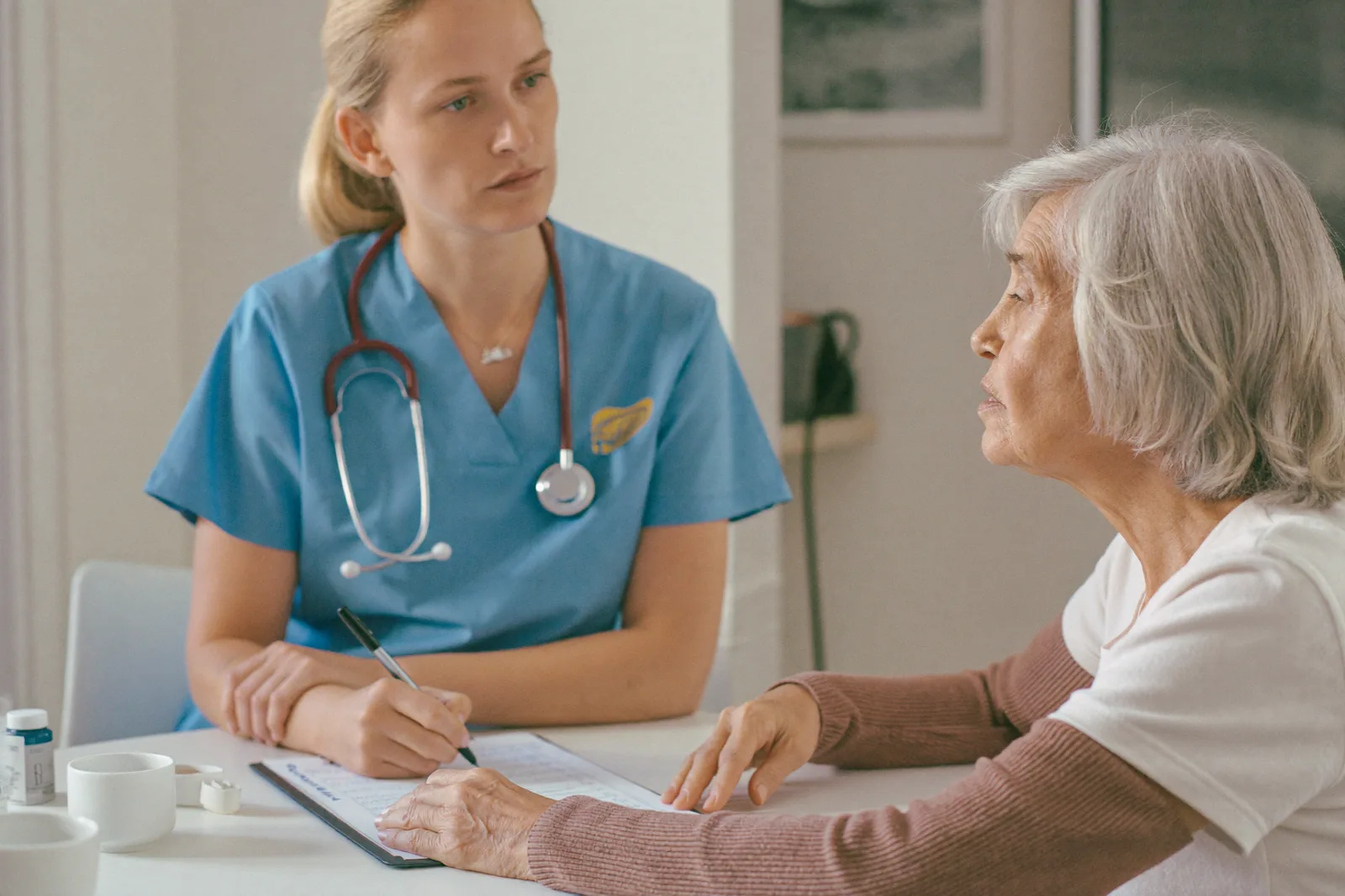 Nurse completing a written assessment with an elderly woman in her new apartment