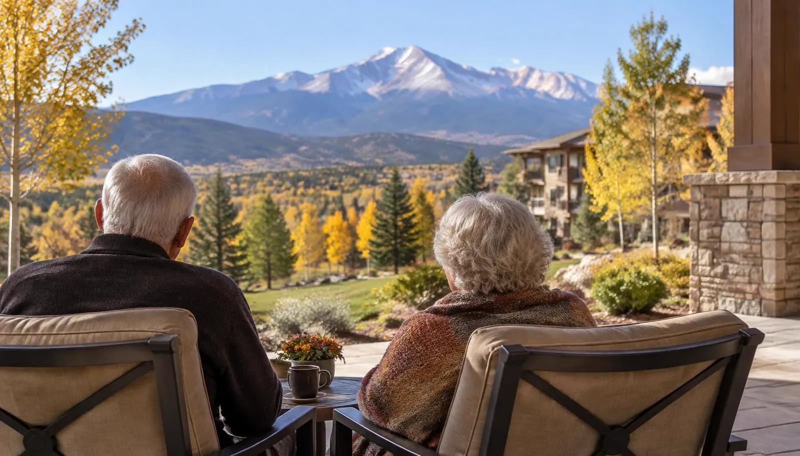 Older couple seen from behind on a senior community patio with Pikes Peak in the distance in early fall
