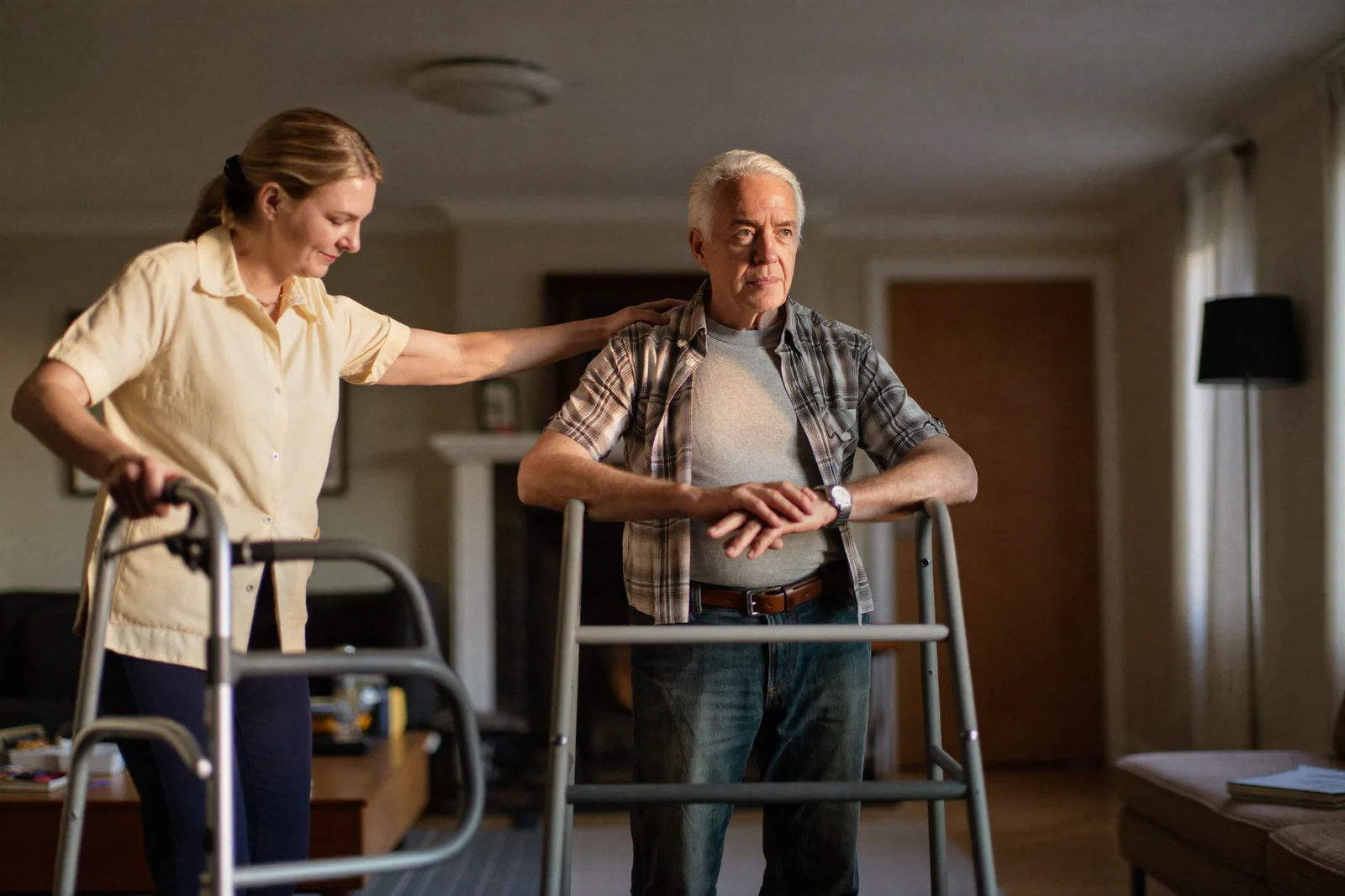 Caregiver helping an elderly man at home with a walker nearby