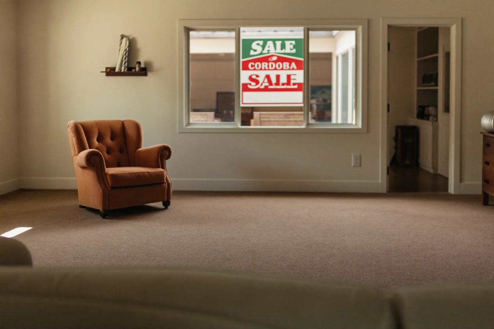 Empty staged living room with a for sale sign outside the window