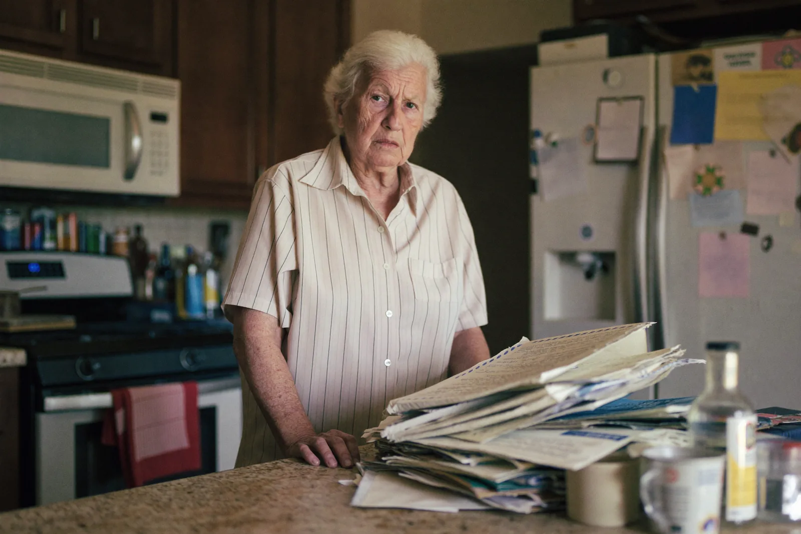 Elderly woman looking uncertain at a stack of unopened mail