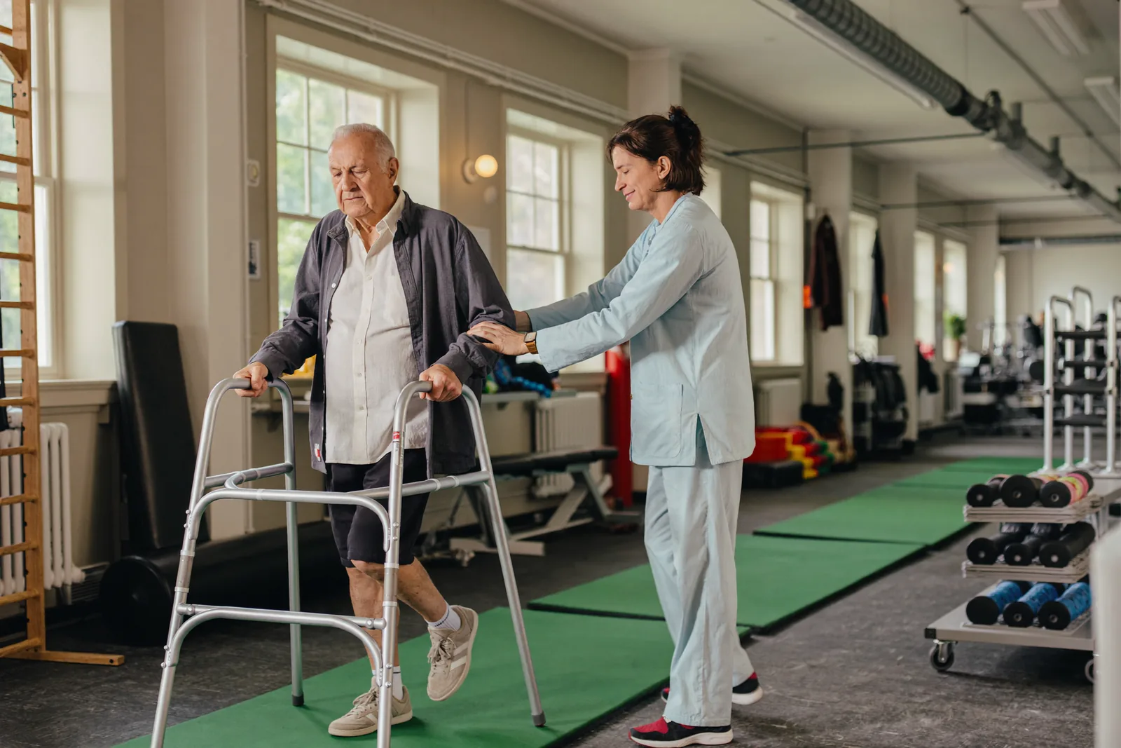 Elderly man doing walker therapy with a physical therapist