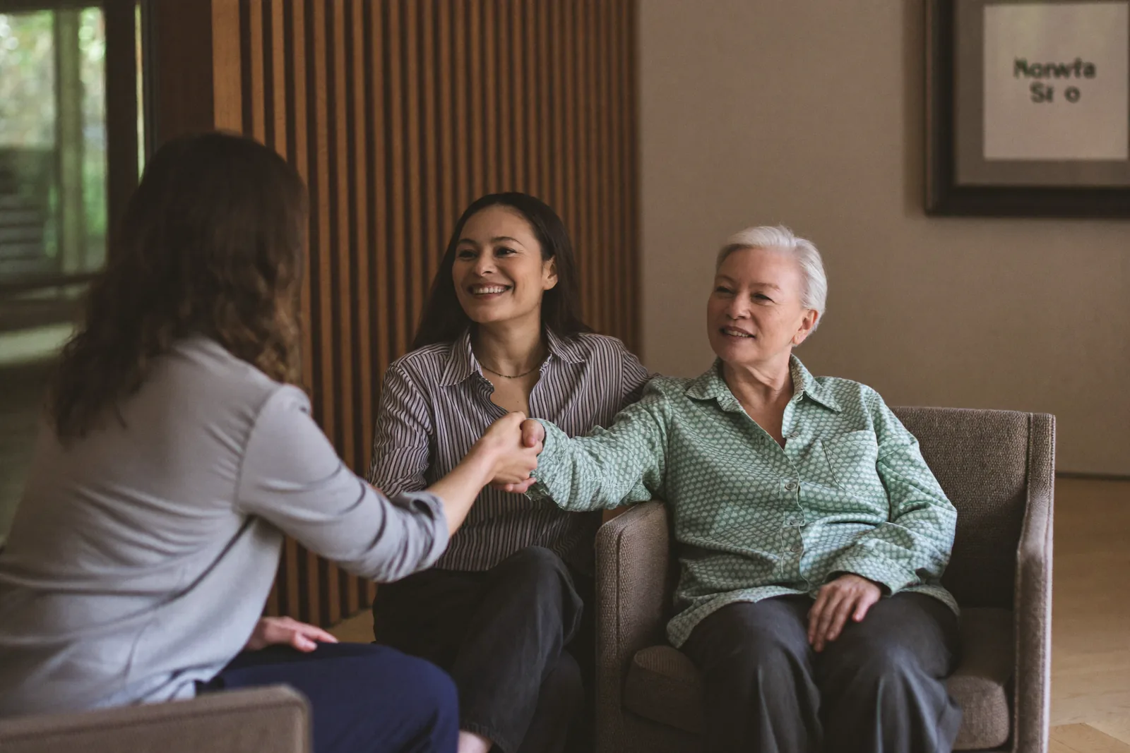 Advisor and family shaking hands in a senior living lobby