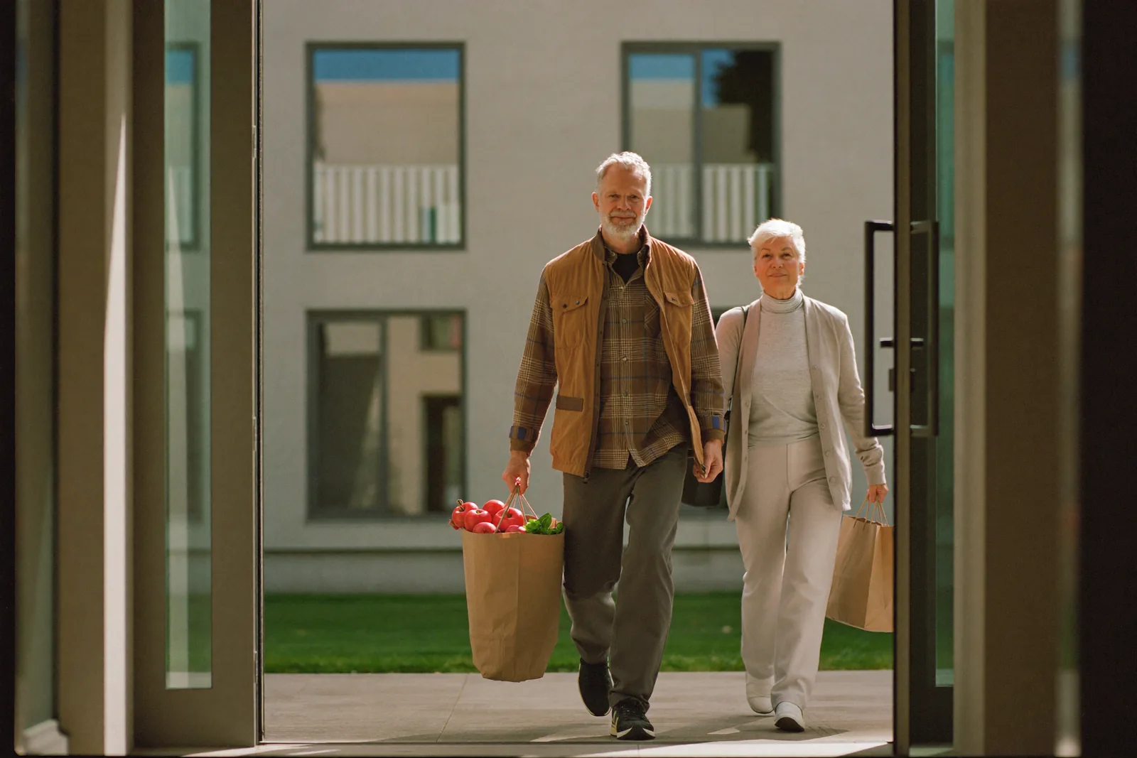 Elderly couple walking into a modern independent living building