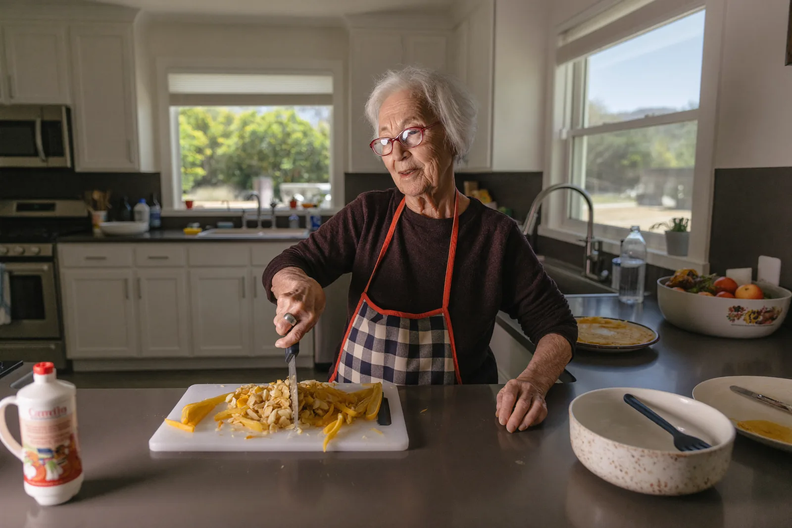 Elderly woman cooking in her own independent living kitchen
