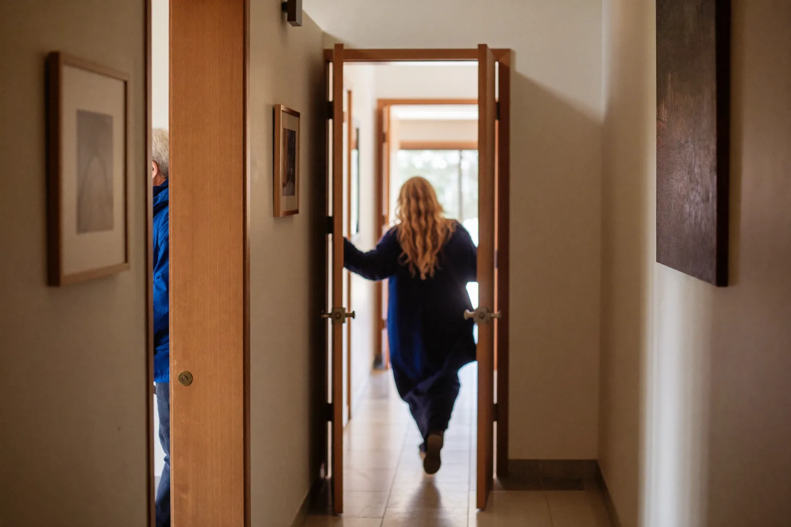 Resident walking through one of three doorways in a bright hallway