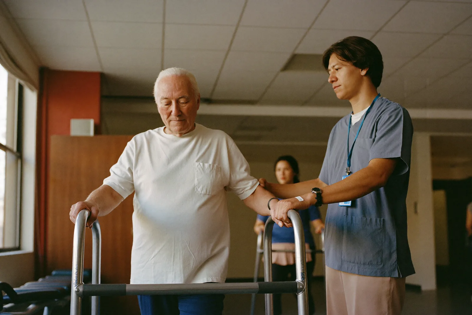 Elderly man practicing steps with a therapist after a hospital stay