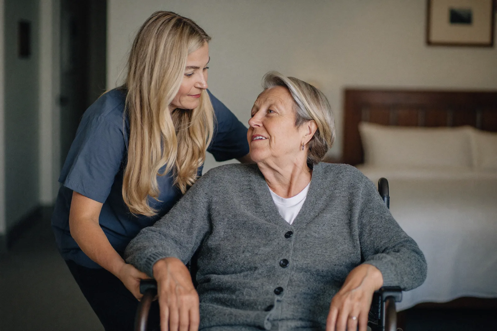Caregiver gently helping a resident with a cardigan