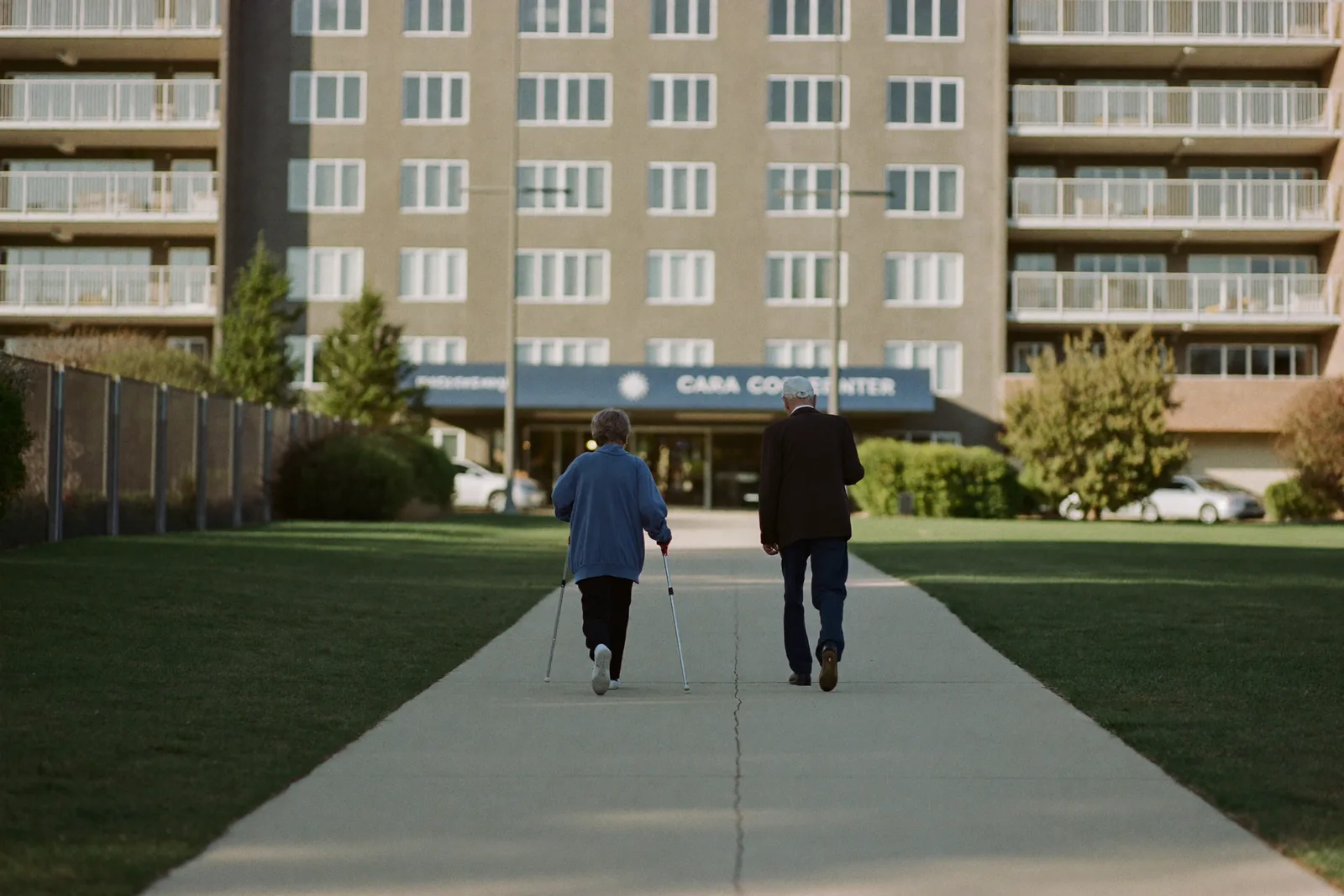 Elderly couple walking a campus path toward the care center