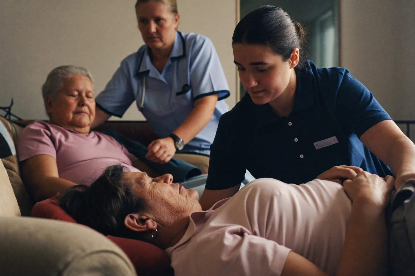 Tired family caregiver resting while a professional caregiver assists